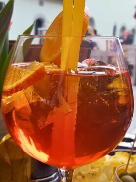 aperol spritz served in a wine glass garnished with orange slice