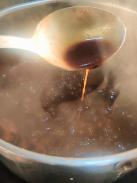 a spoon testing the consistency of a beer and mushroom gravy