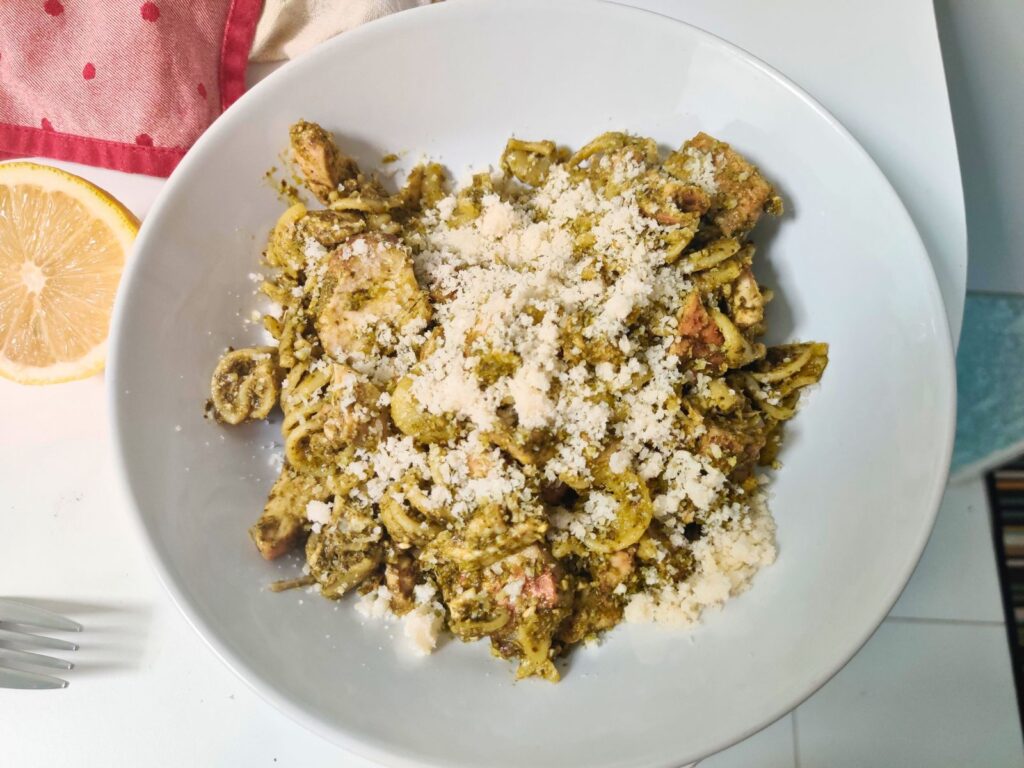 fusilli pasta in pesto sauce covered in cheese on a plate